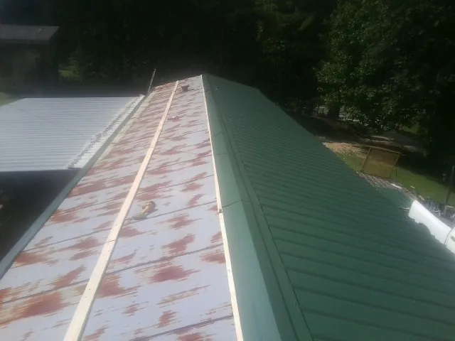 Old rusted panels beside newly installed green metal roofing — Wind Damage Roof Repair by Roofing Brothers in Lima